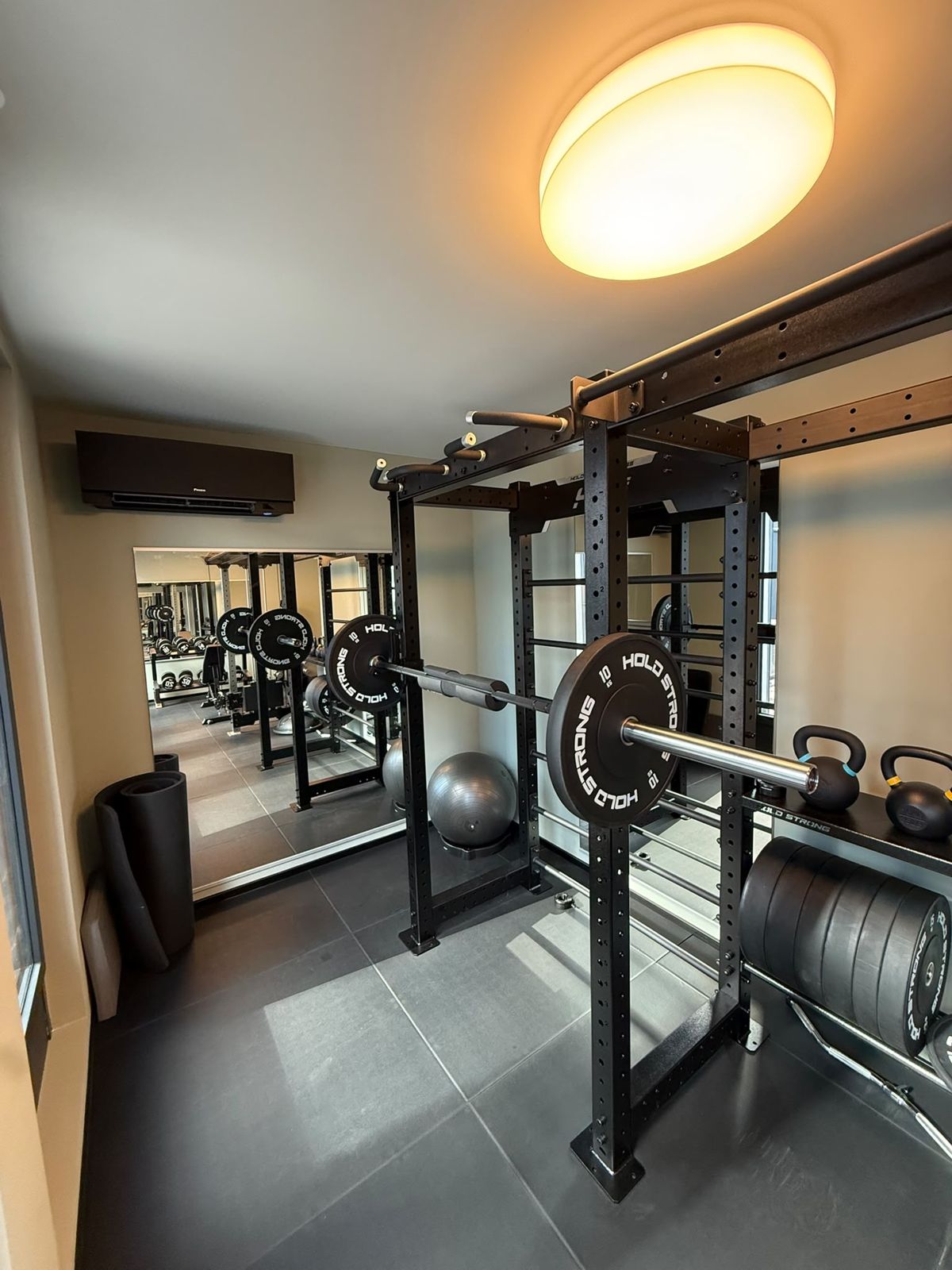 Trainingsbereich der PhysioNova Physiotherapie Frankfurt mit Power Rack, Hantelscheiben und Kettlebells